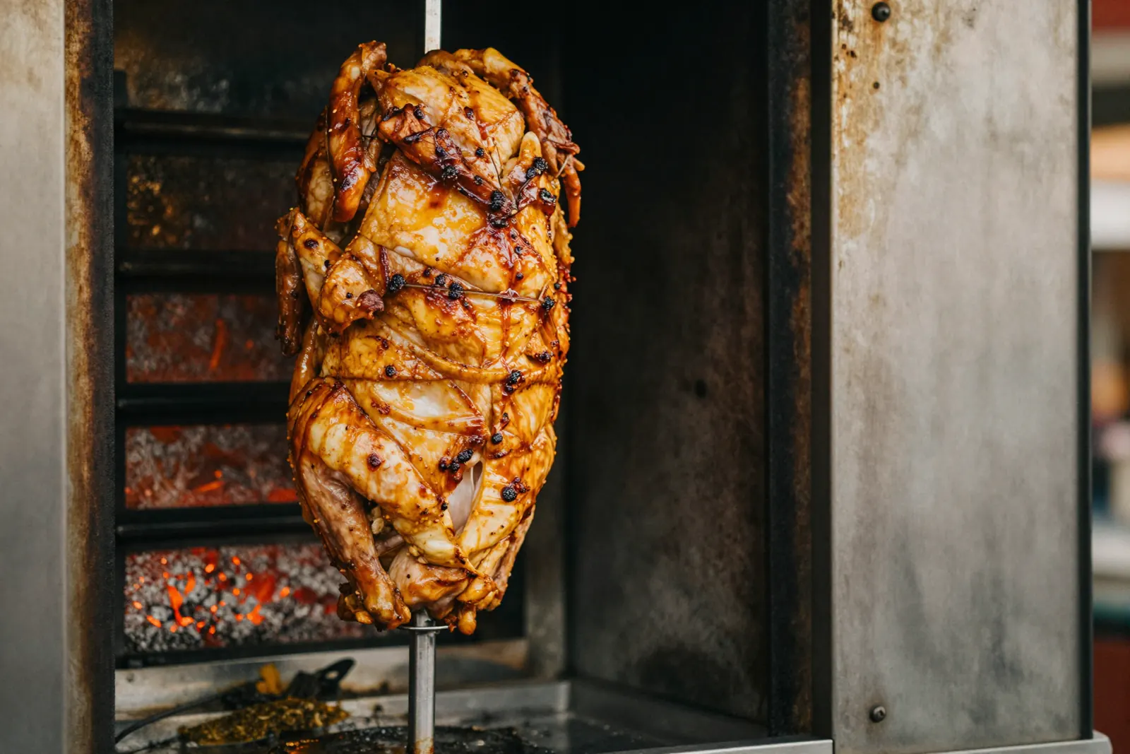 A vertical shawarma spit roasting in front of the grill